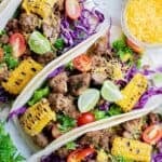 Three homemade ground beef tacos loaded with various toppings.