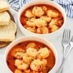 Bowls of shrimp in a buttery tomato herb broth served with bread for dipping.