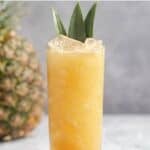 Copycat Soggy Dollar Bar painkiller drink and a pineapple behind it.