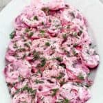 Sliced roasted beets with sour cream sauce on a platter.