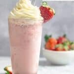 A copycat Starbucks strawberry frappe topped with whipped cream and a strawberry.