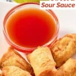 A bowl of red sweet and sour sauce served with egg rolls.