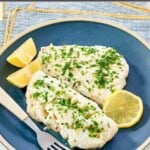Butter poached fish fillets with lemon and herbs on a plate.
