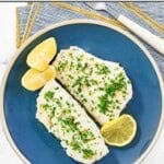 Butter poached fish topped with fresh herbs and served with lemon wedges.