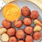 Homemade Captain D's hush puppies and dipping sauce on a plate.