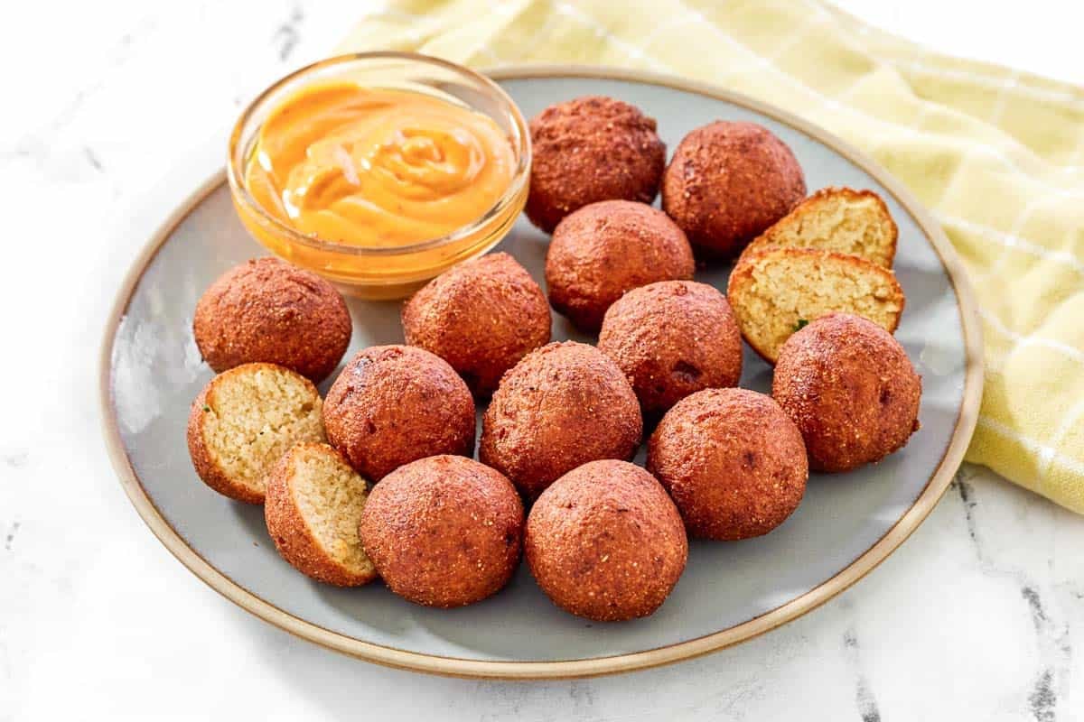 A plate of fried hush puppies with dipping sauce.