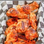 Homemade grilled buffalo chicken wings in a parchment paper lined basket.