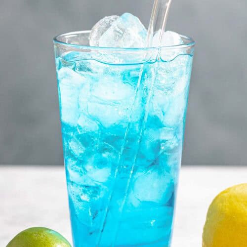 A lemon lime and coconut tropical blue drink in a tall glass.