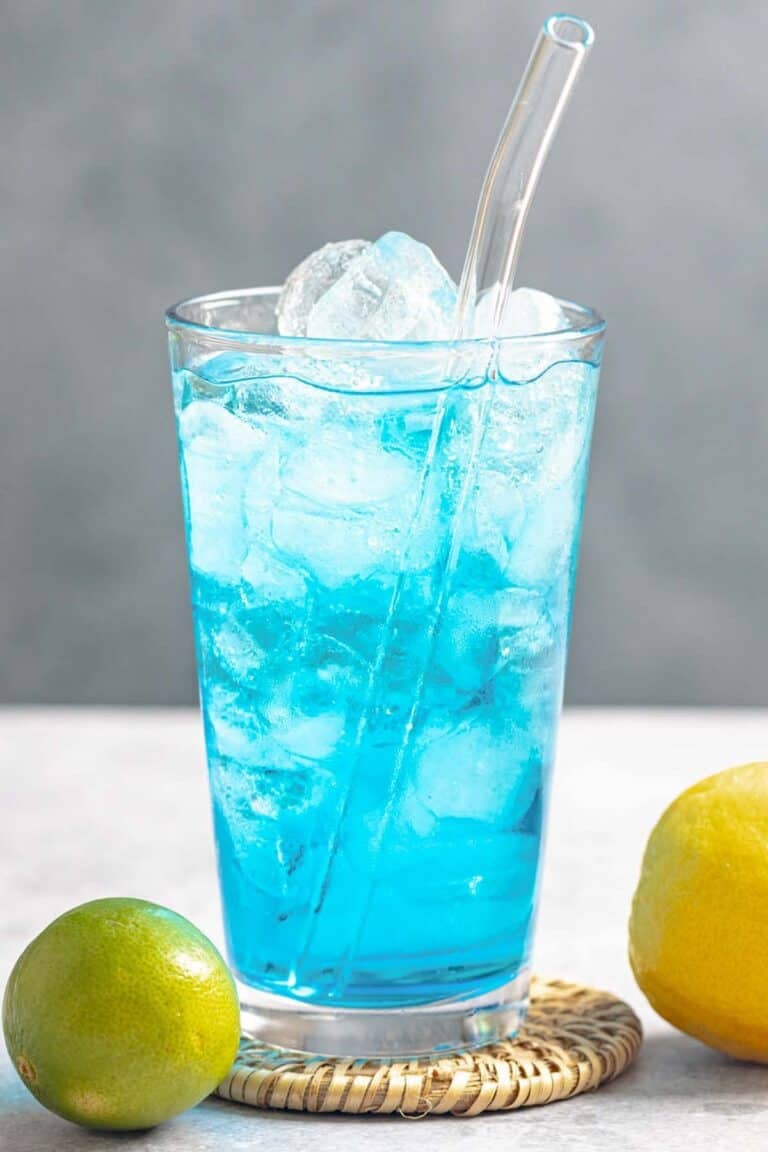 A lemon lime and coconut tropical blue drink in a tall glass.