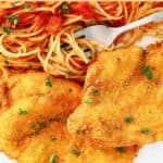 Copycat Cheesecake Factory Chicken Romano served with pasta and tomato sauce.