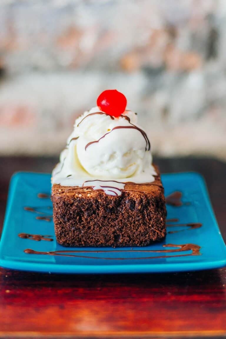 Chocolate brownie topped with ice cream, fudge sauce, and a cherry.