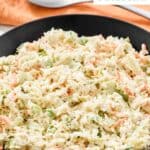 A bowl of copycat Corky's coleslaw and a spoon on a napkin.