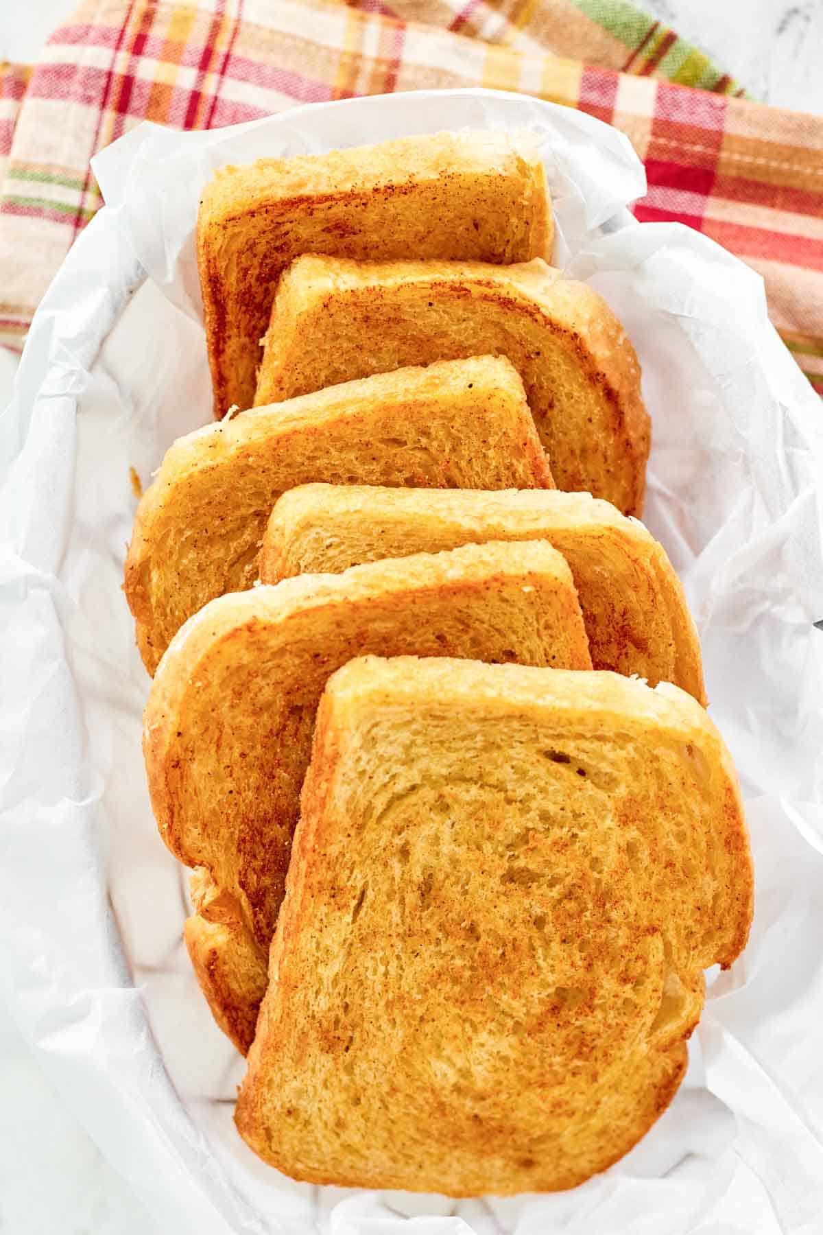 Crispy buttered garlic toast in a parchment paper lined serving basket.
