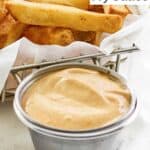 A small cup of Freddy's fry sauce and French fries.