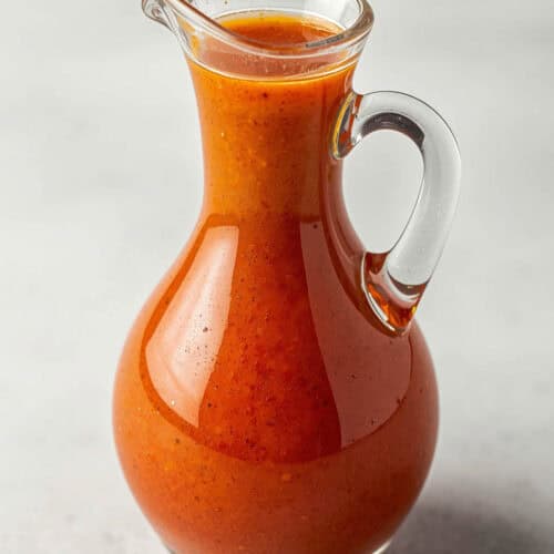 A small pitcher of tomato-based salad dressing.