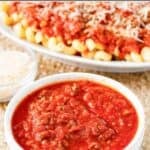 Copycat Olive Garden three meat sauce and a platter of pasta with the sauce.