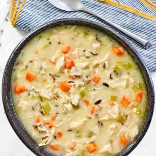 A bowl of thick and creamy soup with chicken, veggies, and wild rice.