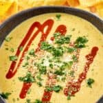 Copycat Torchy's green chile queso topped with cotija cheese, hot sauce, and cilantro.