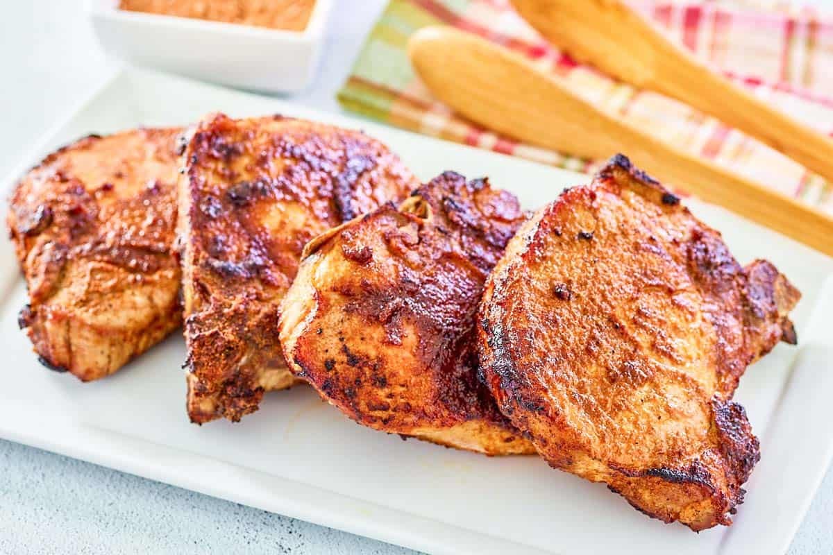 Several air-fried seasoned bone-in pork chops on a rectangular platter.