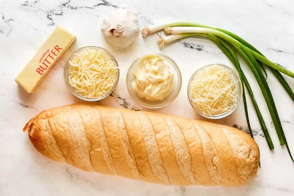 French bread, butter, cheese, mayonnaise, garlic, and green onions.