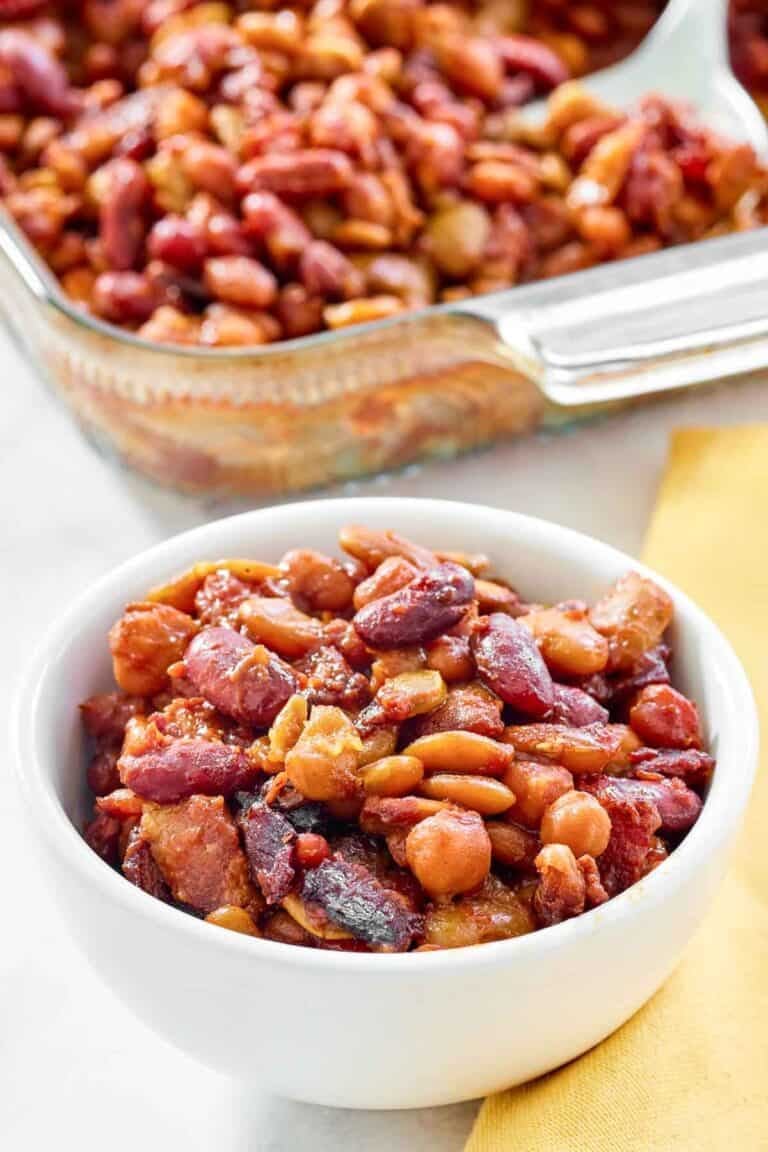 Five bean casserole with bacon in a bowl and glass baking dish.