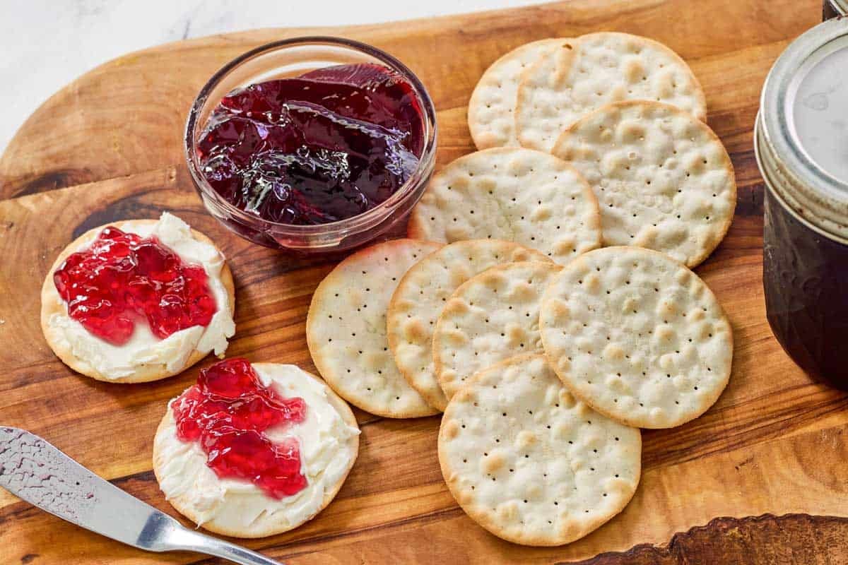 Red wine jelly and crackers on a wooden board.
