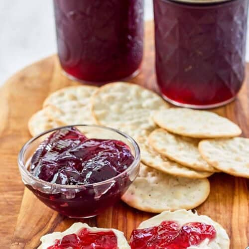 Red wine jelly in jars, in a small cup, and on top of cream cheese crackers.