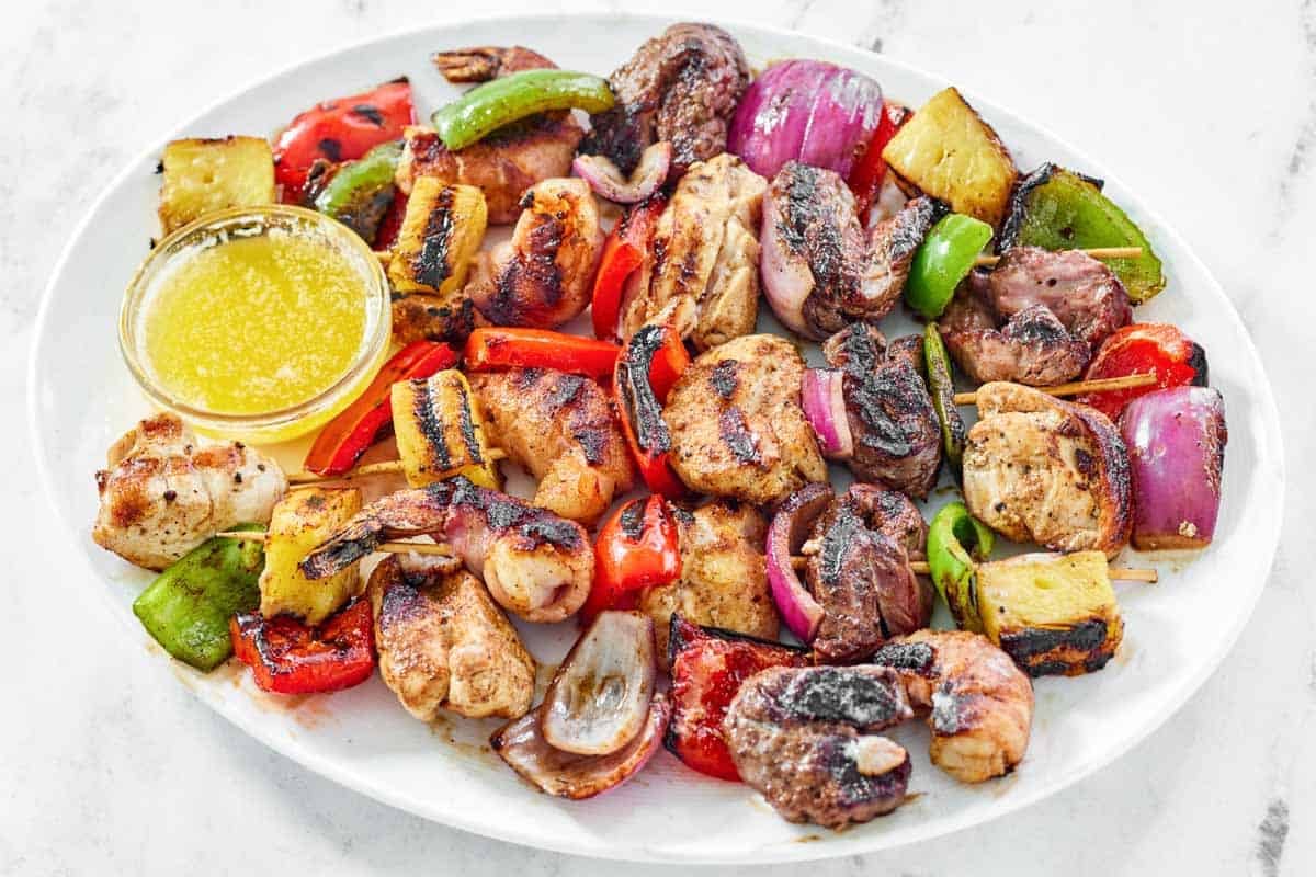 Steak, shrimp, chicken, vegetable, and pineapple fajita skewers with garlic butter sauce.