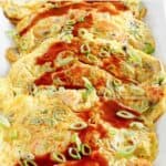 Homemade egg foo young with gravy garnished with green onions.