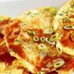 Homemade egg foo young topped with gravy and green onions.