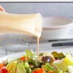 Copycat Houston's buttermilk garlic salad dressing being poured onto a salad.