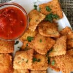 Copycat Olive Garden toasted ravioli and a small cup of marinara sauce for dipping.