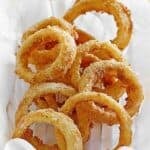 Copycat Sonic onion rings in a wire basket lined with parchment paper.