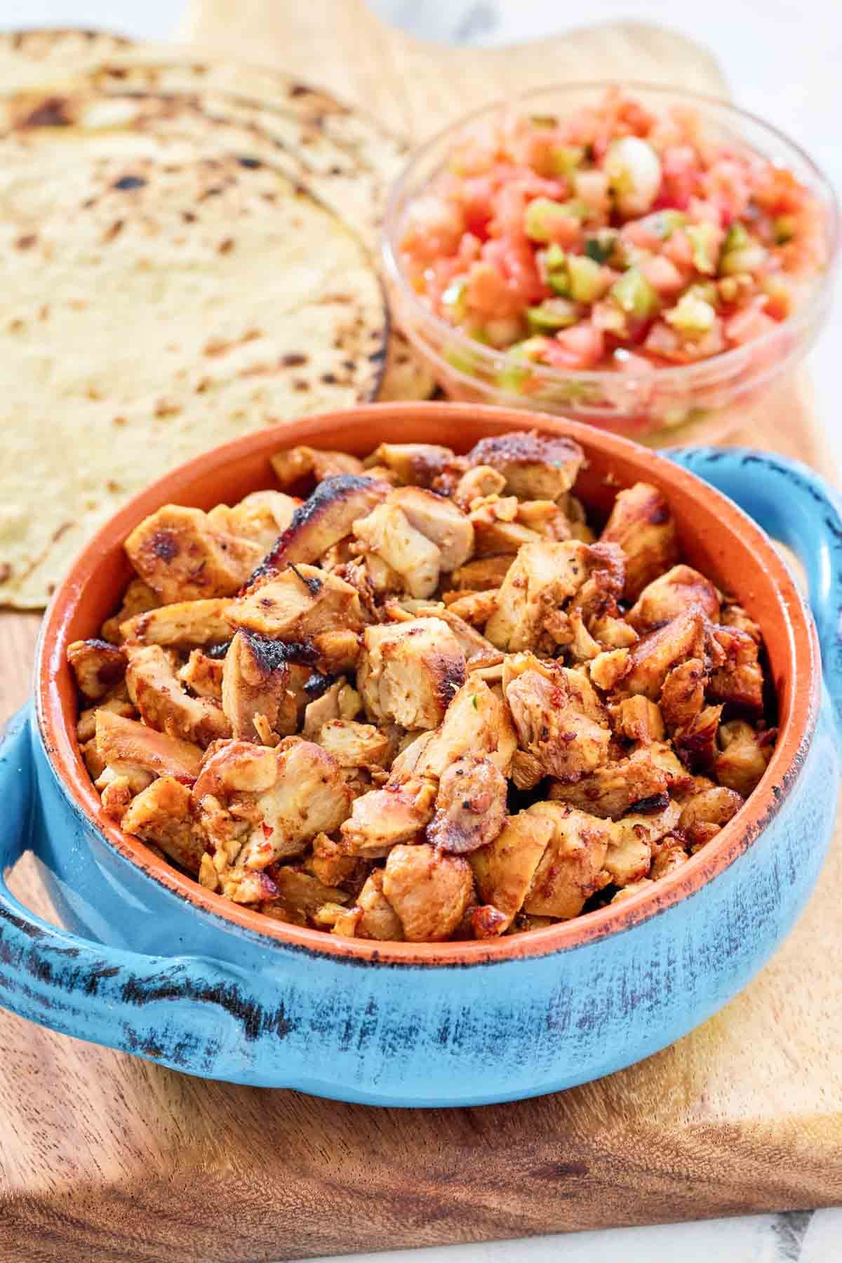 Adobo, chipotle, anchiote pepper, and fruity chicken pieces in a bowl.