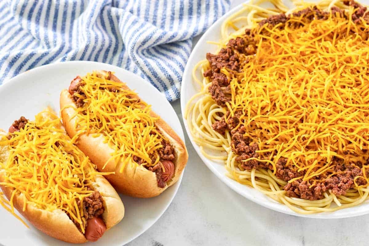 Hot dogs and spaghetti topped with chili and shredded cheese.