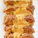 Stuffed meatloaf slices topped with brown gravy on a platter.