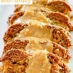 Slices of stuffed meatloaf topped with gravy on a platter.